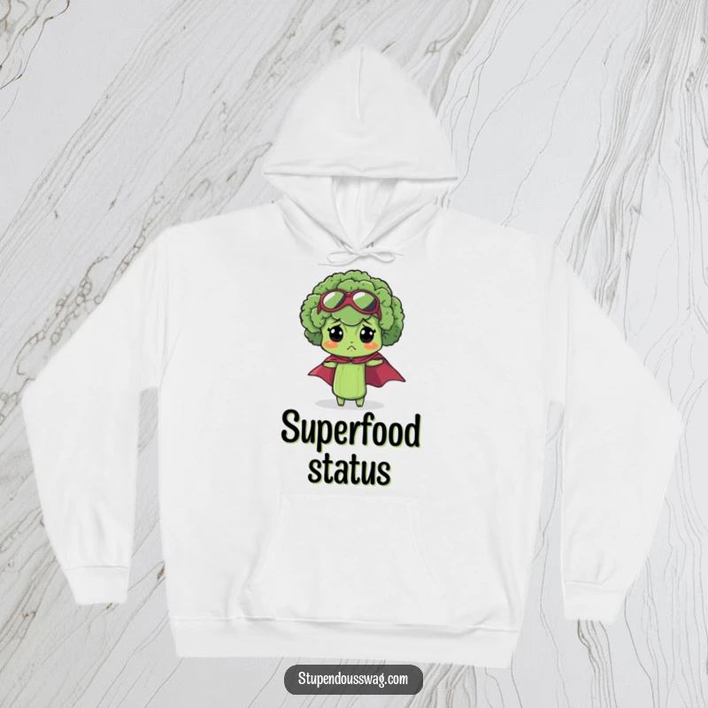 Funny bewildered broccoli hoodie featuring a tiny superhero cape on a slightly confused floret, offering cozy heroic vibes.